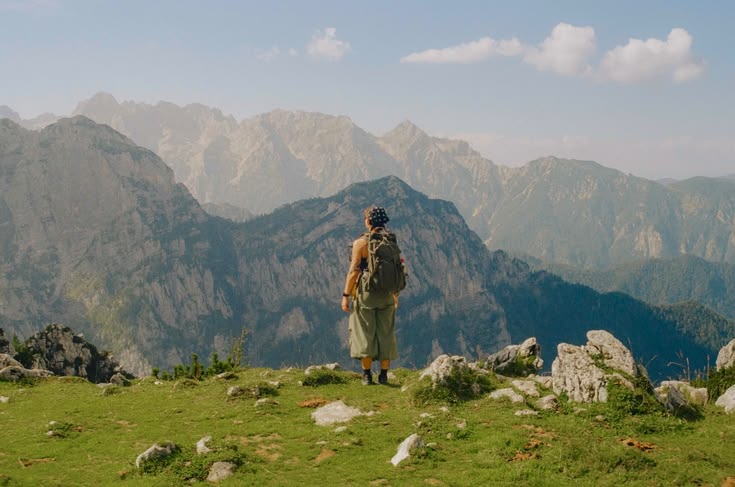 A hiker at a summit looking across a mountain range.