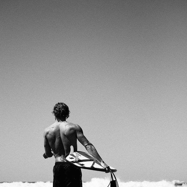 A lone surfer walking toward the ocean at dawn.